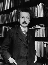 Albert Einstein standing in front of a shelf of books